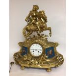 A gilt metal manual clock the top surmounted with