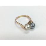 A yellow metal ring set with two pearls, one white