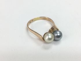 A yellow metal ring set with two pearls, one white