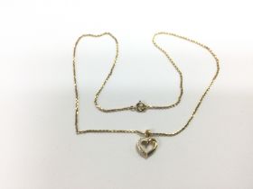 A yellow metal heart shaped pendant on a chain, ap