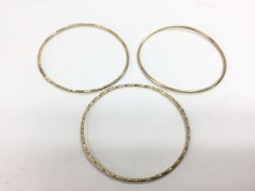 A set of three gold bangles with textured decorati