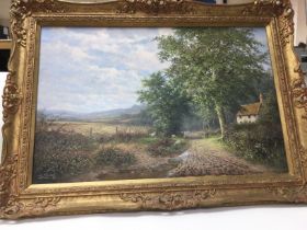 A gilt framed oil painting of a rural view painted