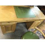 An oak pedestal desk with green leather centre and matching chair. Desk is approx 150cm wide by 70