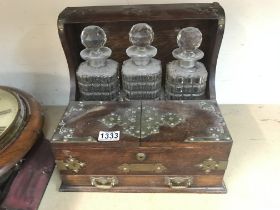 A oak Tantalus inset with three decanters together