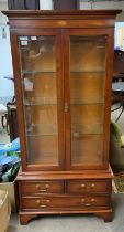 A modern glazed display cabinet with 3 draw sectio