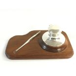 A silver hallmarked inkwell and dip pen on a wooden stand. Both engraved with initials MSV.