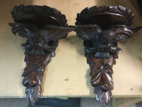 A pair of carved wall brackets in the form of eagl