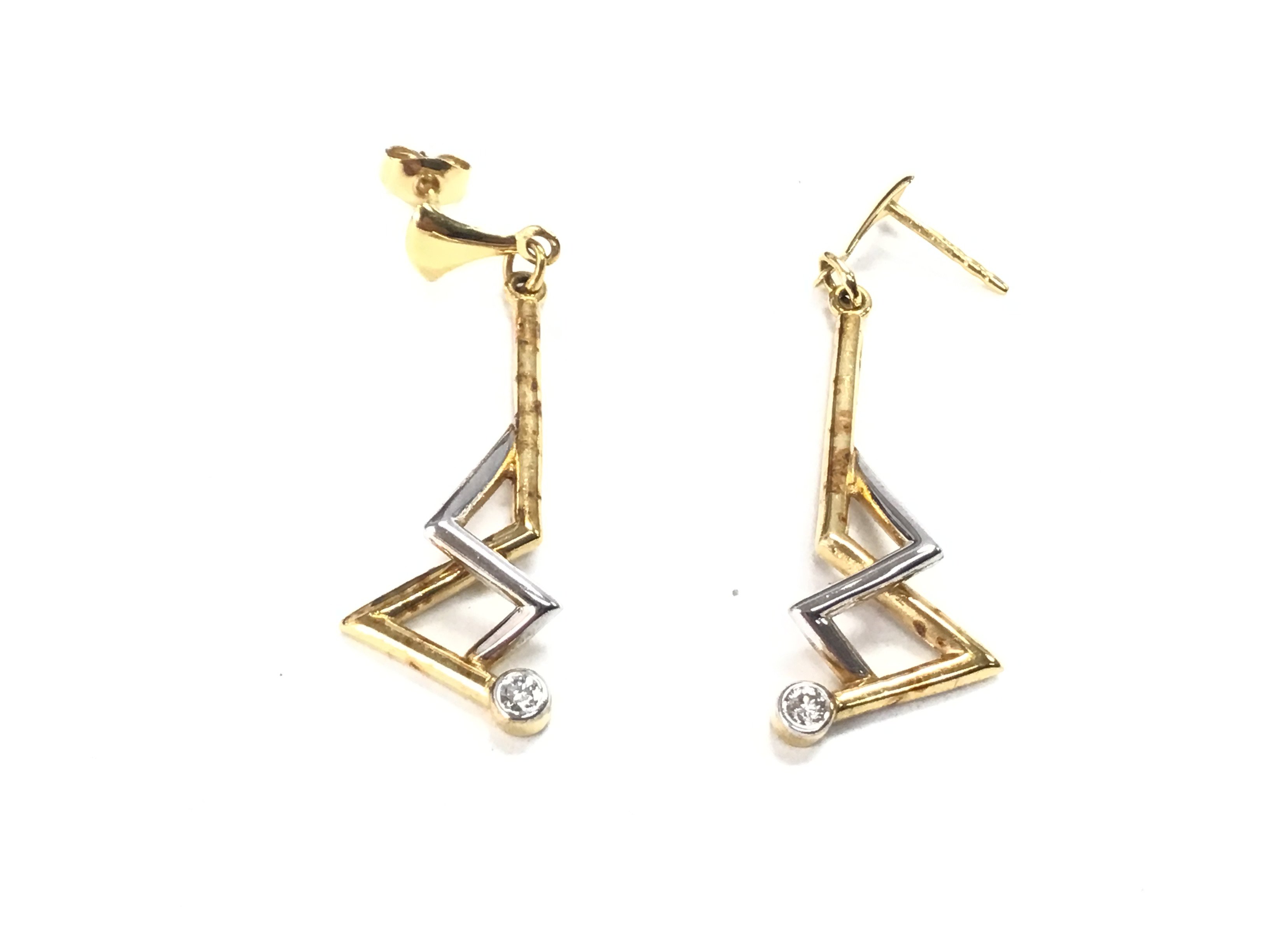 A pair of gold earrings set with a diamond. Total