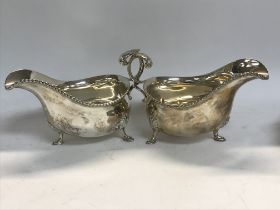 A pair of silver gravy boats with c scrolling handles on shaped feet .317 grams.