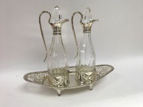 A pair of glass bottle cruets with silver rims inset into a oval silver stand Chester hallmarks 1904