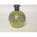 A yellow glass perfume bottle with floral design with silver lid .
