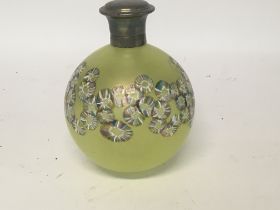 A yellow glass perfume bottle with floral design with silver lid .