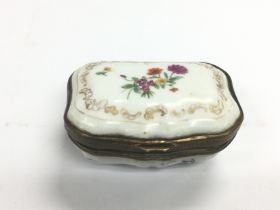 A small hand painted ceramic pill box with a paint