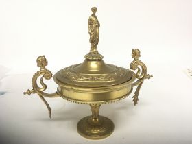 A Neo Classical gilt metal urn the lid with a raised figure flanked by scroll supports height