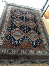 A hand knotted rug with a geometric lozenge pattern with red and blue field