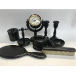 A ebonized dressing table set including clock candle sticks mirror, brush tidy jar ring tree .