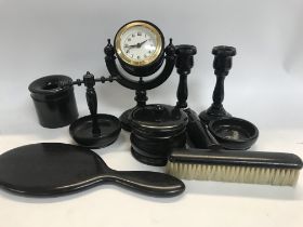 A ebonized dressing table set including clock candle sticks mirror, brush tidy jar ring tree .