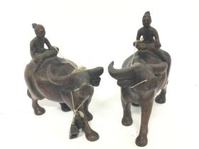 Indonesian buffalo and rider hardwood figurines, 14cm tall.