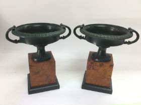 A pair of classical urns raised on squared wooden bases, approx height 20cm. Shipping category B. NO