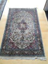 A Persian part silk hand knotted rug with a central medallion on an ivory field with a perfusion