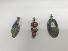 Three silver stone set pendants.