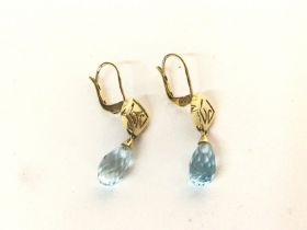 A pair of gold earrings with cut aquamarine drops.
