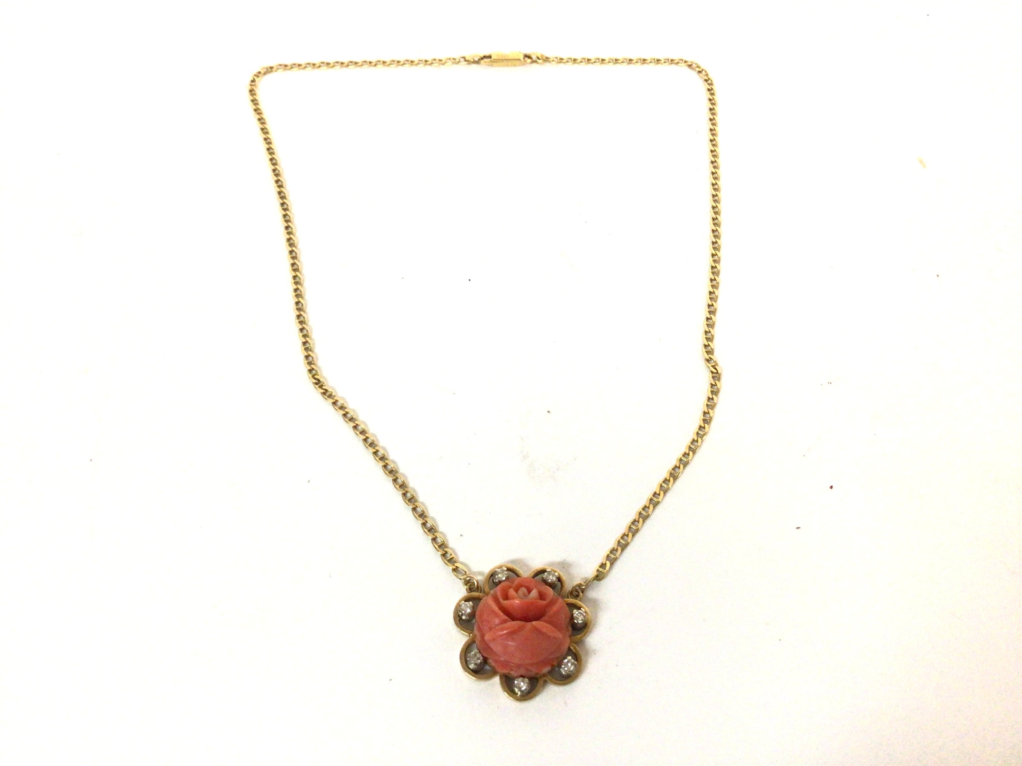A coral and diamond pendant on a chain. Both marke