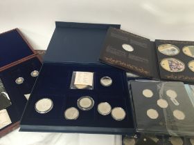 A collection of cased coins including small gold commemorative coins coin checker 50 pence pieces