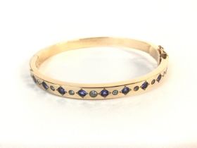 An unmarked gold bangle set with alternating Tanza