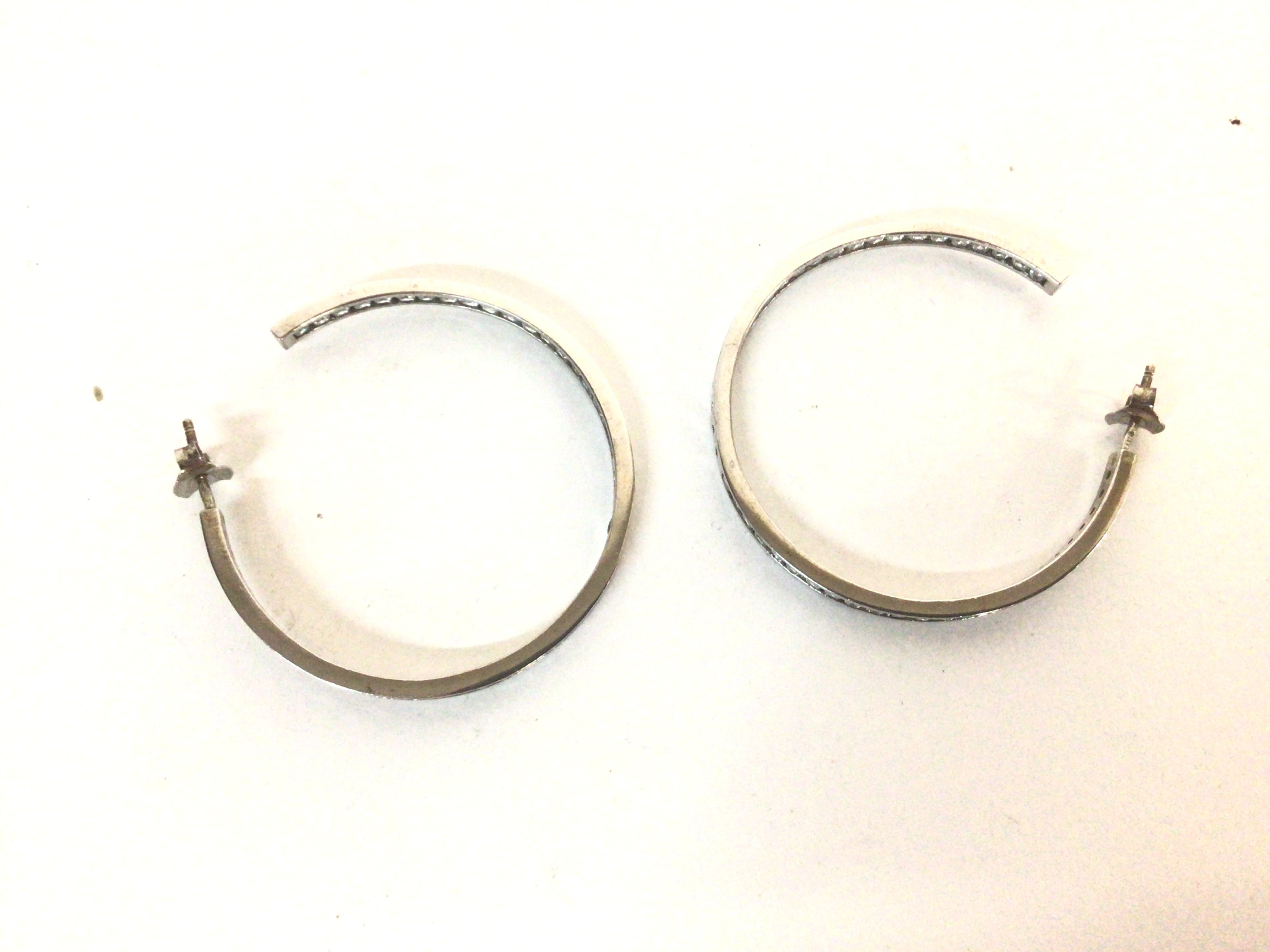 A pair of silver hoop earrings set with white ston