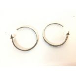 A pair of silver hoop earrings set with white ston