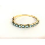 An 18ct gold bangle set with aquamarine. 15.64 and