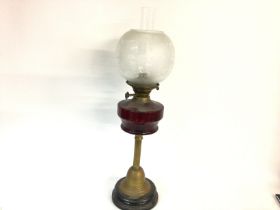 A cranberry glass oil lamp. No damage noted. 70cm