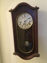 A small modern wall clock with a visible pendulum