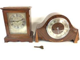 An oak mantle clock with a silver dial and a walnu