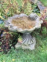 A weathered composition shell shape bird bath and