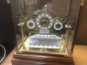 A modern brass Mystery clock under a glazed case .