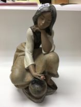 A large Lladro figure of a seated girl.