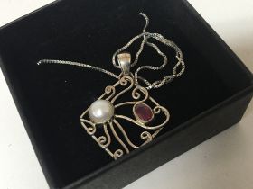 A silver necklace with an open pendent set with pe
