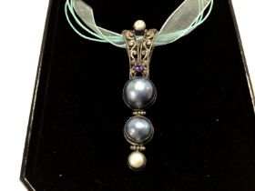 A silver pendant with cultured pearls and purple g