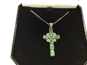 A silver chain with a cross pendant inset with gre