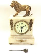 An Alabaster mantle clock topped with a gilted lio