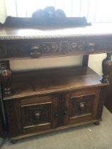 A carved late Victorian oak buffet with a raised b