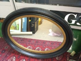 Two ebonised and giltwork wall mirrors comprising an oval shaped example, approx width 87cm and