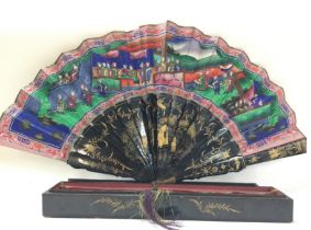 A boxed Chinese fan decorated with figures, flower