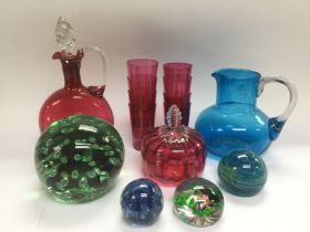 A collection of coloured glass ware comprising a cranberry glass decanter and eight tumblers,