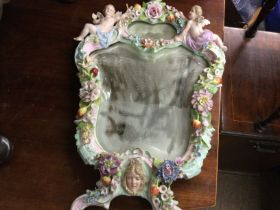 A German porcelain wall mirror with raised cherubs