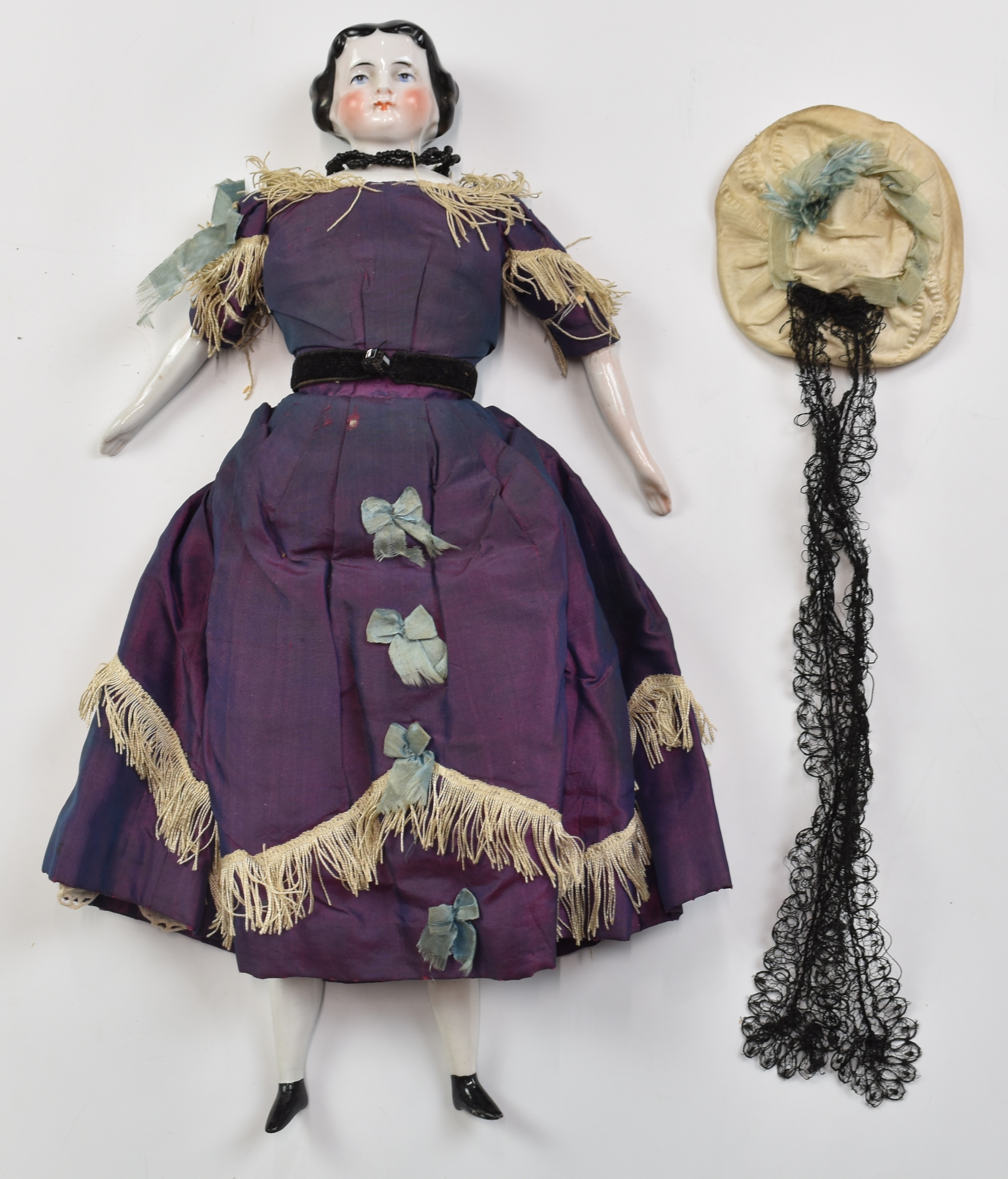 19th / early 20thC German porcelain doll wearing period purple silk dress with blue bows,