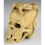 Japanese Meiji period signed carved bone okimono of a skull with a toad and serpent surmount and