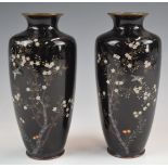 A pair of Japanese cloisonné vases decorated in enamel with birds, trees and flowers on a dark